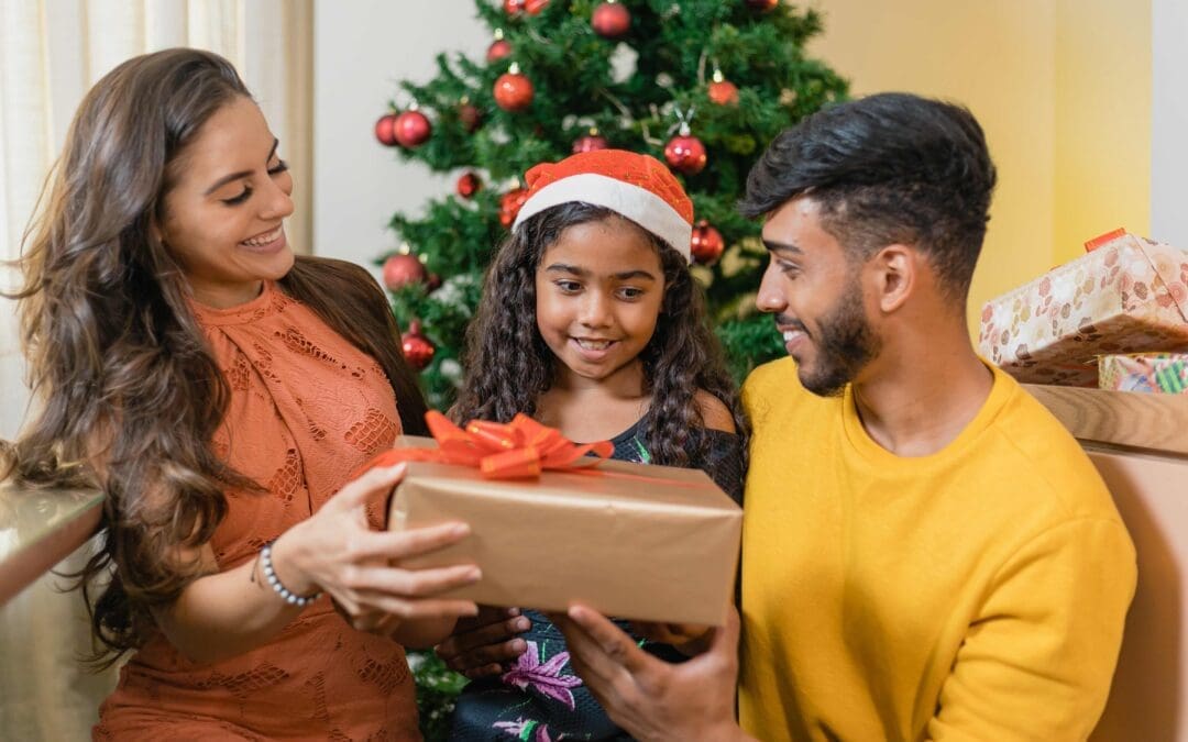 family giving curly haired child a christmas gift