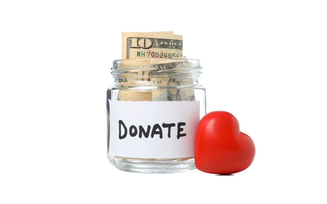 Red heart beside a donate glass jar with money isolated on white background