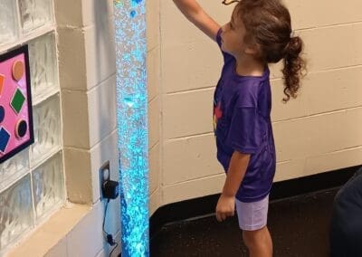 Girl playing with tall sensory lamp with fish in it at Christ Chapel Church